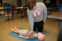 Student practicing CPR on child manikin